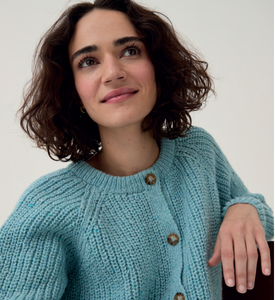 Woman wearing a light blue Sirdar 10780 Loveful 100% Recycled Tweed Double Knit cardigan with buttons on a plain background