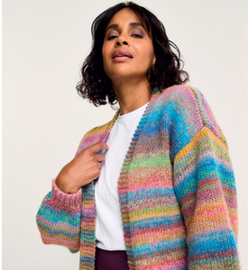 Woman wearing a multi-coloured Sirdar 10801 striped cardigan against a plain background