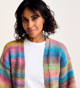 Woman wearing a colourful Sirdar 10801 Jewelspun Chunky knitted cardigan against a white background