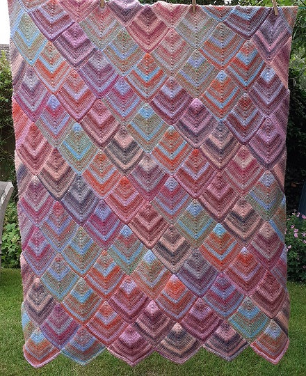 A multi coloured blanket knitted using Sirdar Jewelspun yarn and our stocking stitch domino blanket knitting pattern.